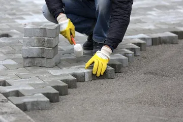 A dedicated man works on a sidewalk, laying bricks with precision to build a strong and inviting walking surface.